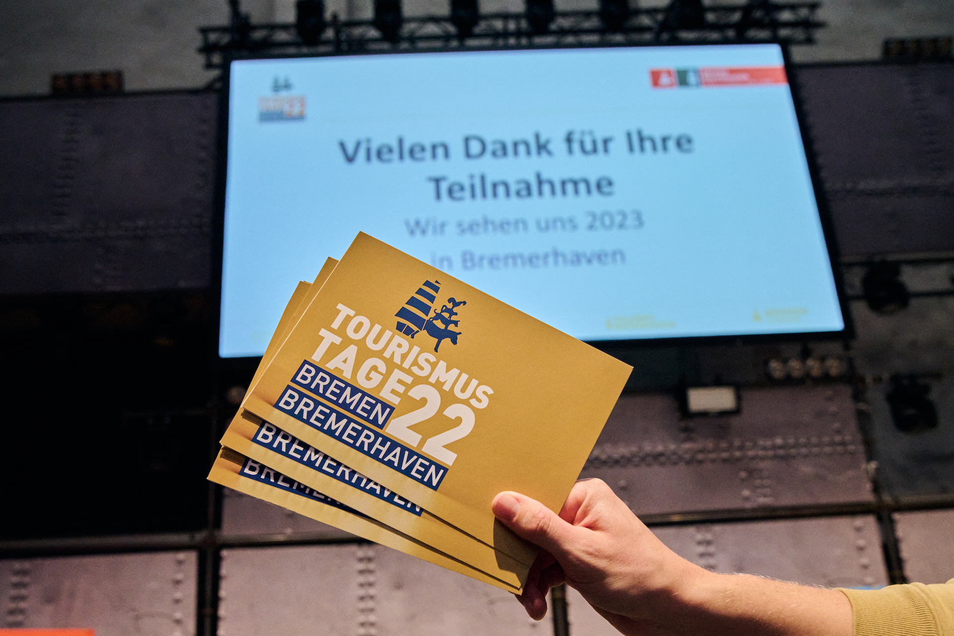 Eine Hand hält drei Karten in Der Hand. Auf diesen Karten steht Tourismustage 2022 Bremen Bremerhaven